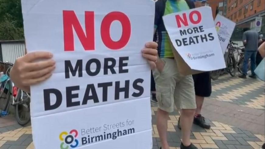 A sign held up by a protestor reads "no more deaths", next to them is another protestor with an identical sign