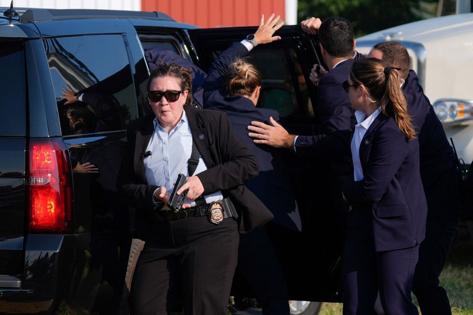 Republican presidential candidate former President Donald Trump is surrounded by U.S. Secret Service agents as he is taken to a vehicle at a campaign rally, Saturday, July 13, 2024, in Butler, Pa. 