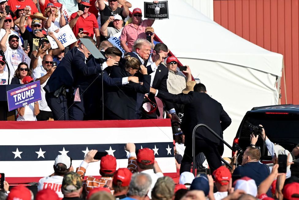 Former US President Donald Trump is surrounded by Secret Service agents during a campaign event at Butler Farm Show Inc. in Butler, Pennsylvania, US, on Saturday, July 13, 2024. 