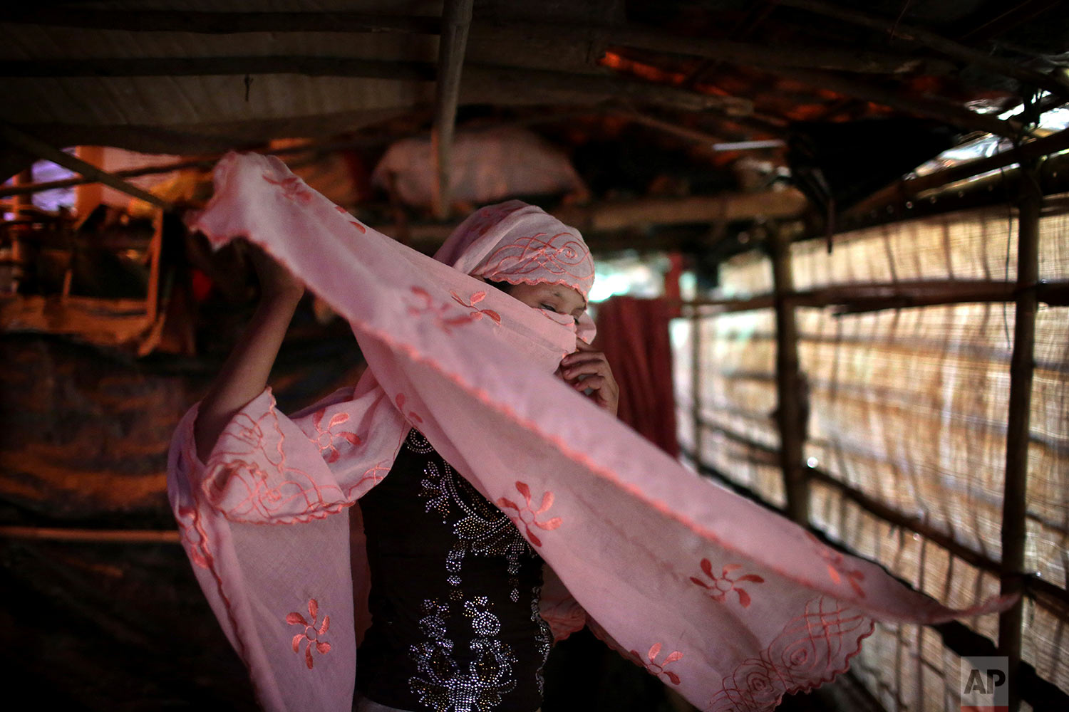   In this Sunday, Nov. 19, 2017, photo, R, 13, who says she was raped by members of Myanmar's armed forces in late August, adjusts her headscarf while photographed in her family's tent in Kutupalong refugee camp in Bangladesh. (AP Photo/Wong May
