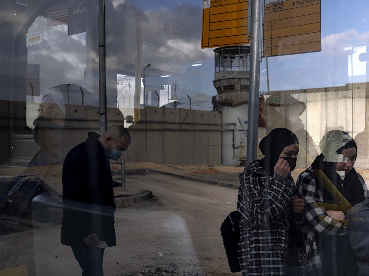  Palestinian commuters get on a bus next to a section of Israel's separation barrier after crossing into Israel through Qalandia checkpoint between the West Bank city of Ramallah and Jerusalem, Jan. 31, 2022. (AP Photo/Oded Balilty) 