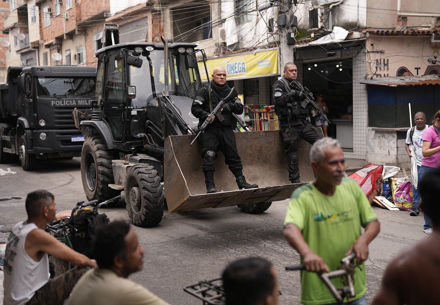  Police ride in the scoop of a bulldozer as they work to clear street barricades during a security operation against organized crime in the Mare Complex favela of Rio de Janeiro, Brazil, Oct. 9, 2023. (AP Photo/Silvia Izquierdo) 