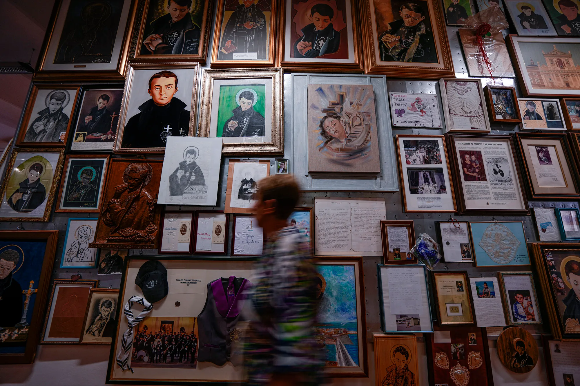 A wall covered in framed religious artwork and documents