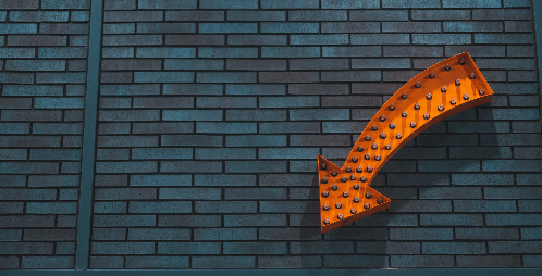 This is an image of an orange arrow pointing down against a wall