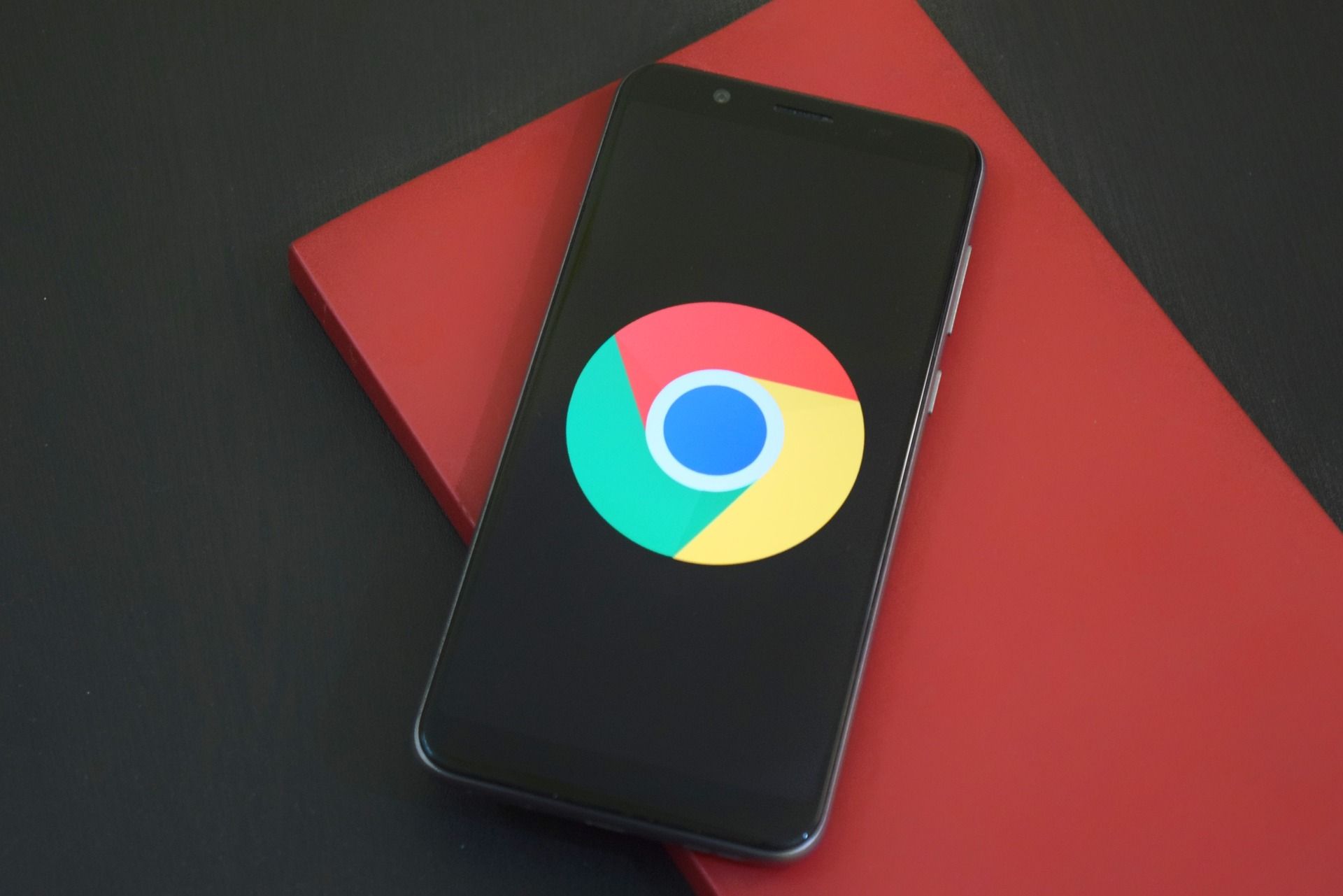 chrome logo on phone display laying on red book cover