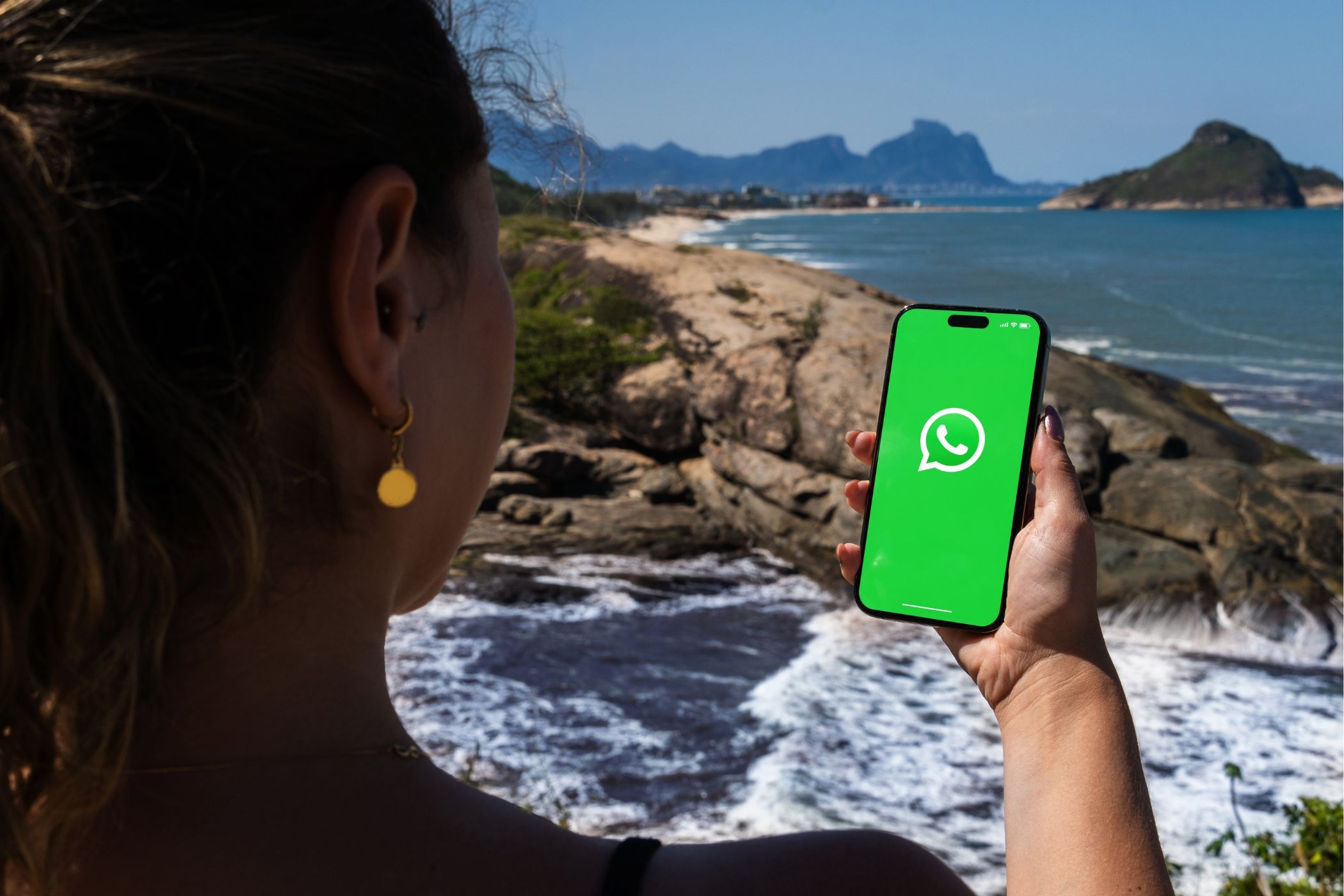 a woman using whatsapp on a smartphone with a beach in the background