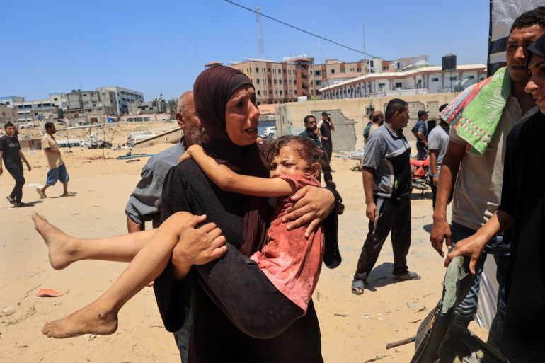 A Palestinian woman carries an injured child to the Nasser hospital in Khan Yunis