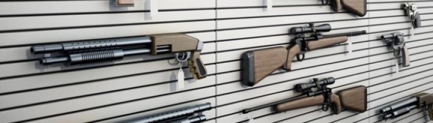 Guns hanging on a wall in a gun store.