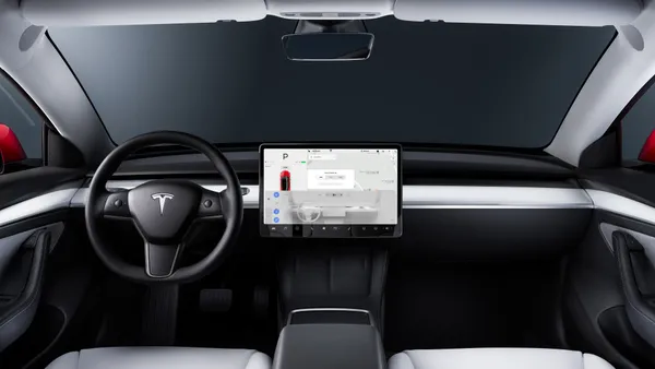The interior and dashboard of the Tesla Model 3 with the white seat color option.