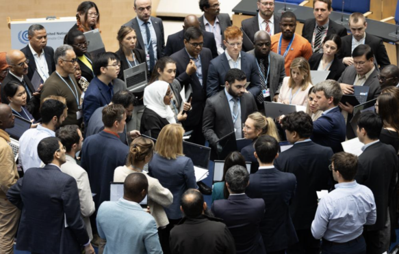 Delegates huddle during consultations on Paris Agreement Article 6.8.