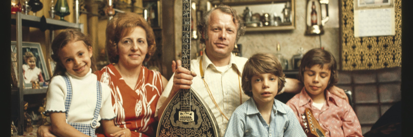 A man holding a guitar posing with a woman and three children