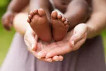 child feet in adopted parents hands