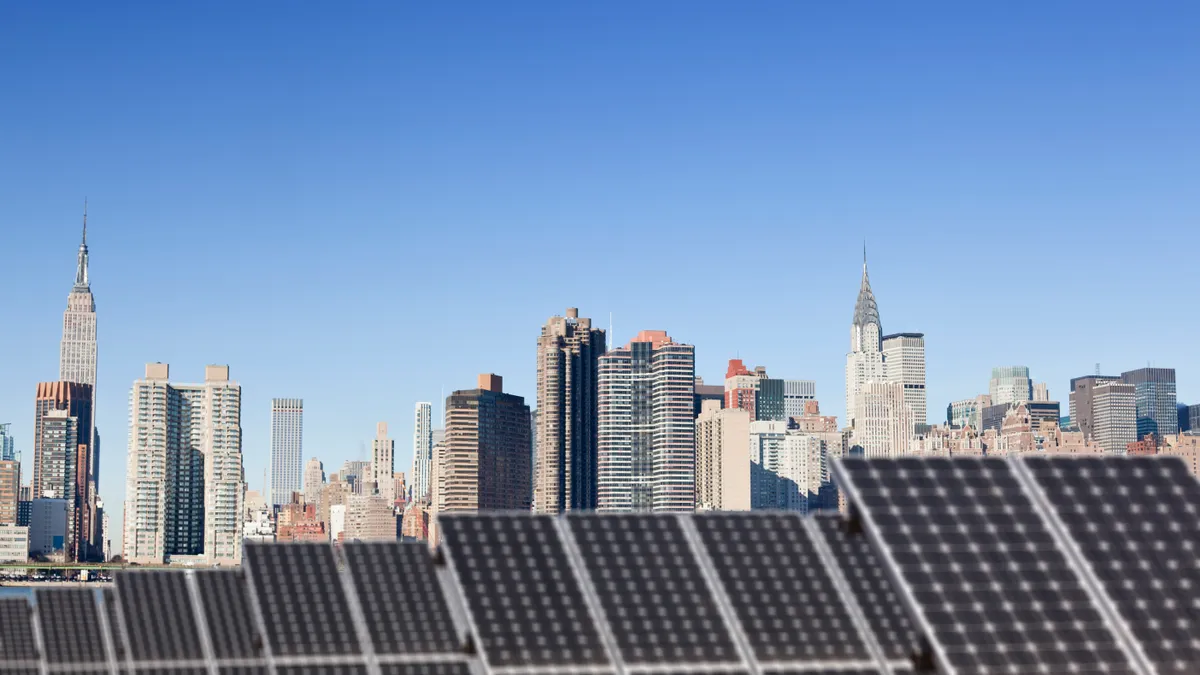 A rooftop solar installation against the backdrop of the Chrysler Building and the Empire State Building in midtown Manhattan.